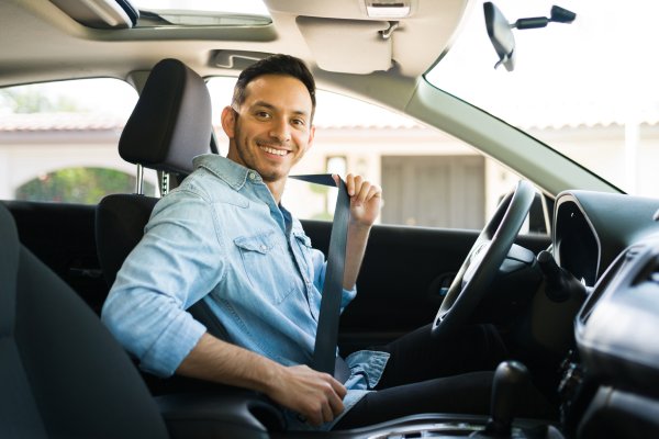 Portrait of an attractive latin man smiling before starting to work as a taxi driver of a car sharing service on a mobile app