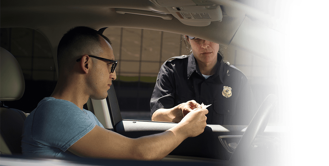 A man takes a driving test with a police officer present at the DrivingQuest course.