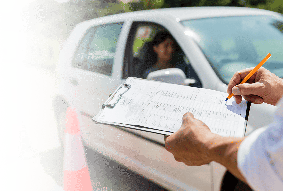  A man sitting in a car writes on a clipboard, preparing for his driving test in Texas.
