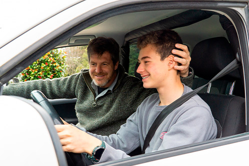 A man and a boy inside a car, focused on mastering the Texas driving test requirements.