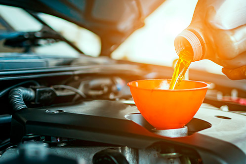 Individual adding oil to a car engine, highlighting key maintenance tips for teen drivers in Texas.