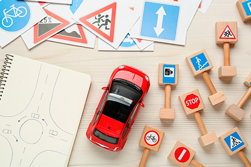 A wooden table with various toy cars and traffic signs, representing essential driving tips and tricks for Texas drivers.