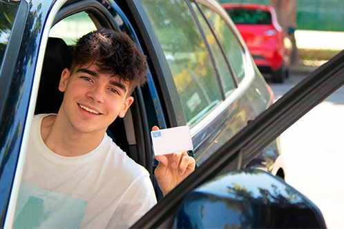 A young man in the driver's seat of a car, reviewing tips for maintaining a Texas Driving Record.