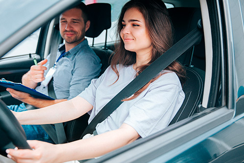A man and woman seated in the front of a car, both focused on the road ahead, representing safe driving practices.