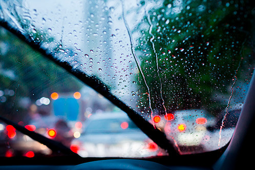 A close-up of a car windshield covered in raindrops, illustrating the challenges of driving in Texas fall weather.