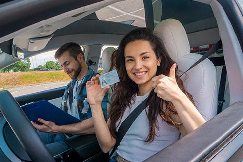 A woman and man in a car, both smiling and giving thumbs up, representing positivity after the Texas DPS Exam.