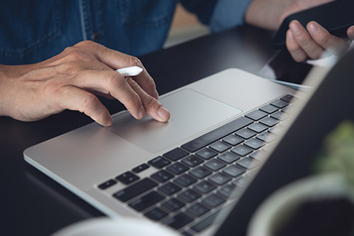 A person typing on a laptop, focused on information about renewing or replacing a Texas driver's license.