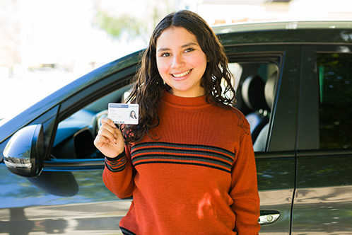 A woman displaying her driver's license, relevant to the topic of renewing or replacing a Texas driver's license.