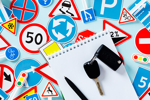 A notebook, pen, keys, and a traffic sign, representing the 2026 changes in Texas driving laws for teens and adults.