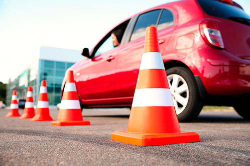 A red car is parked next to orange traffic cones, highlighting a context related to upcoming Texas driving law changes.