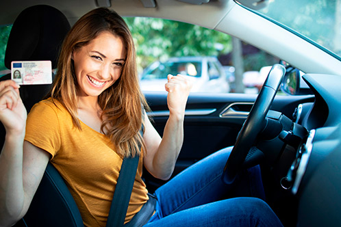 A woman sitting in her car, holding her driver's license, illustrating upcoming Texas driving law changes for teens and adults.