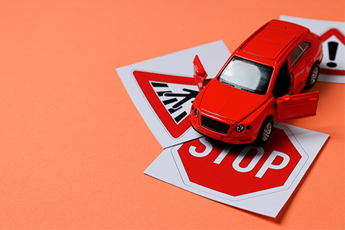 A red toy car placed atop a stop sign, illustrating the importance of traffic rules in Texas Defensive Driving Online.