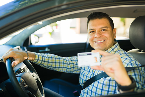 A man displaying his driver's license, highlighting the benefits of defensive driving for reducing Texas car insurance costs.