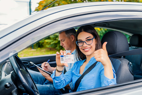 A woman wearing headphones is seated on a couch, using her laptop to research Texas defensive driving insurance savings.