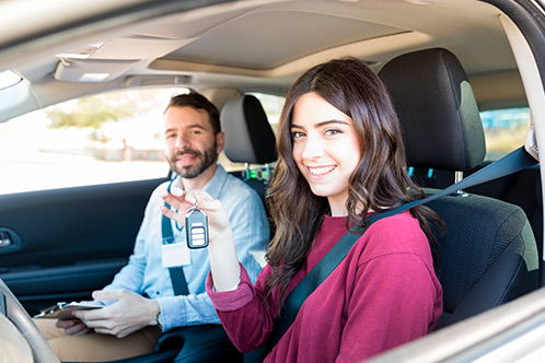 A man and woman in the driver's seat of a car, engaged in a discussion about Texas Adult Drivers Ed in Spanish.