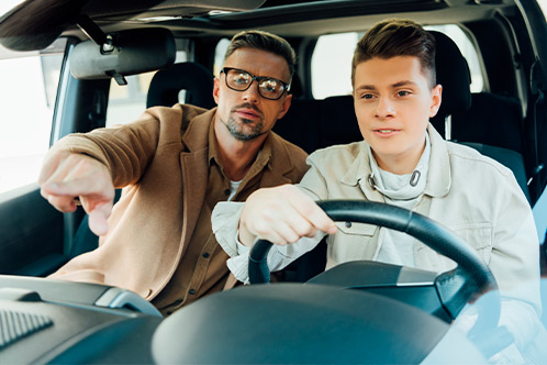 Two men inside a car, with one gesturing towards the camera, related to Texas Parent Taught Drivers Ed checklist.