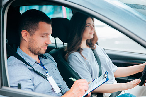 A man and woman inside a car, examining a clipboard for online Texas driver information.