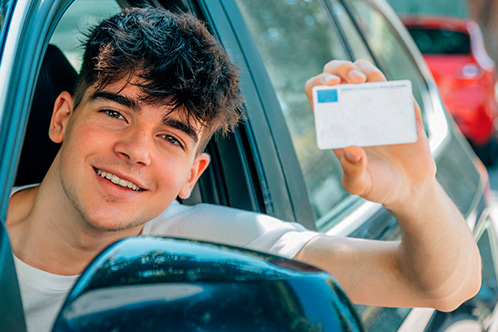 A young man holds up a driver license.
