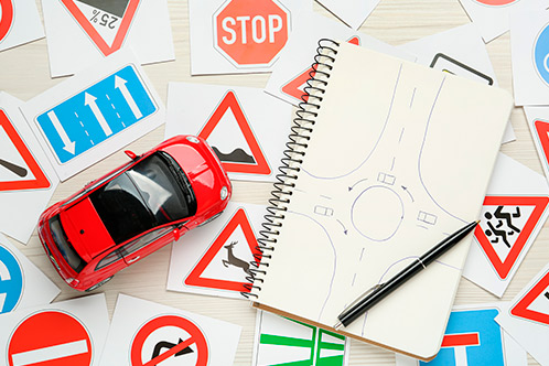 A notebook featuring a small car placed on it, encircled by multiple traffic signs representing different driving regulations.