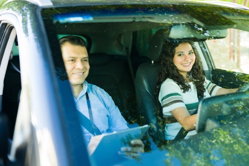 Teenage girl learning to drive with a driving instructor evaluating her performance during a driving test lesson