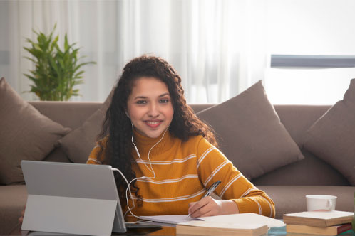 A HAPPY TEENAGER LOOKING AT CAMERA DURING ONLINE CLASS
