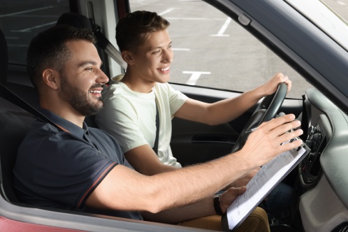 Driving school. Happy student passing driving test with examiner in car at parking lot