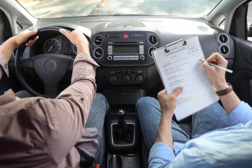 Male examiner with instructor passing driving license test in car