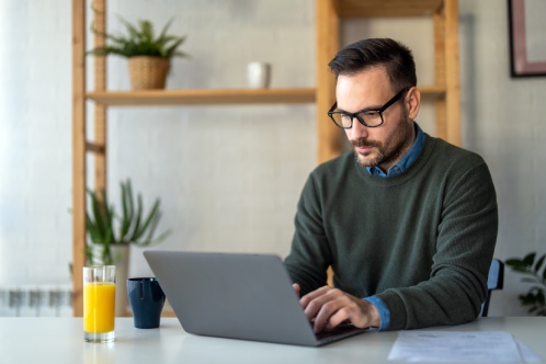 Success man typing on laptop, communicating online distantly working or studying on computer at home
